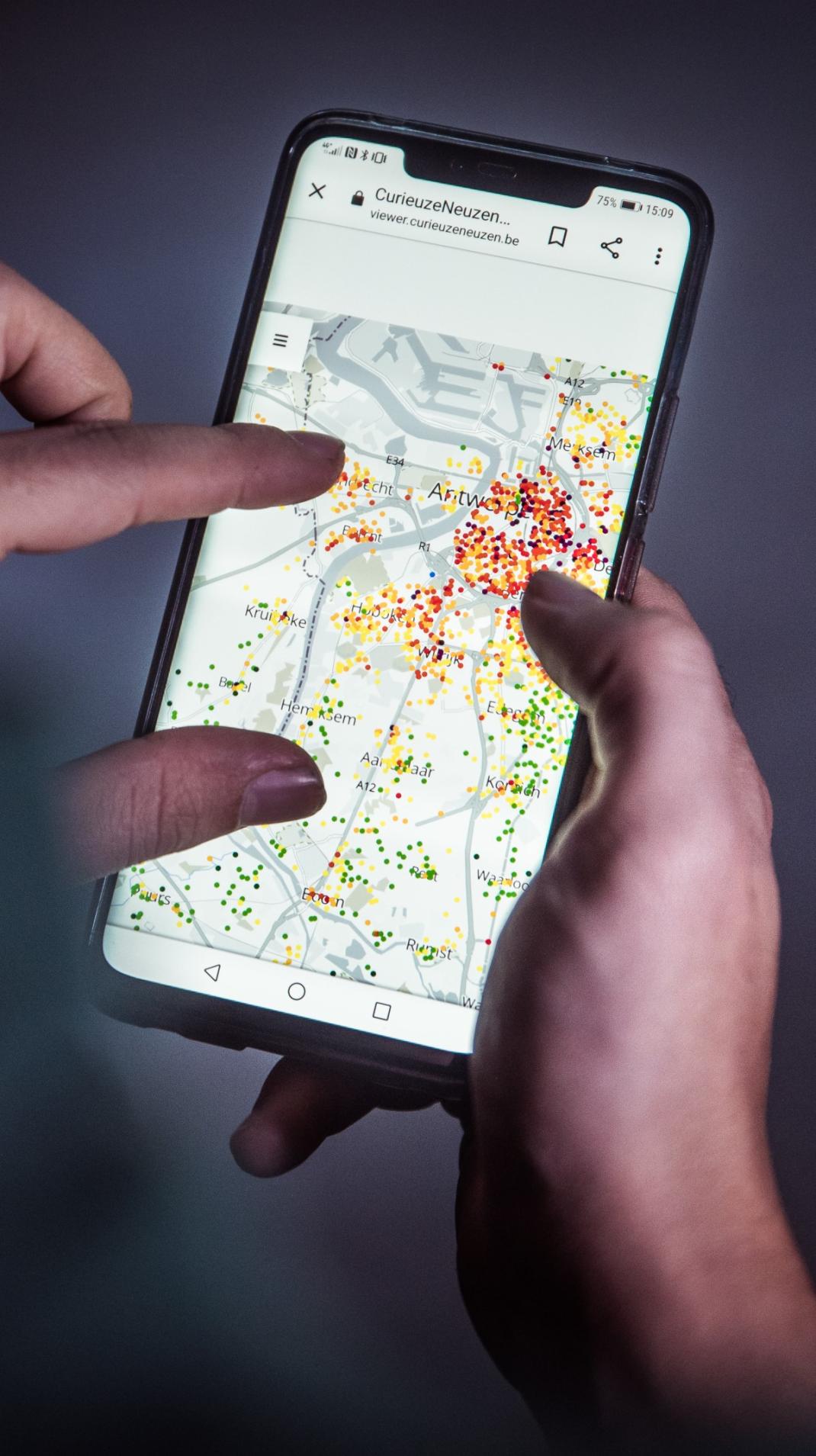 Smartphone scherm met gekleurde bolletjes die de luchtkwaliteit weergeven op een kaart.