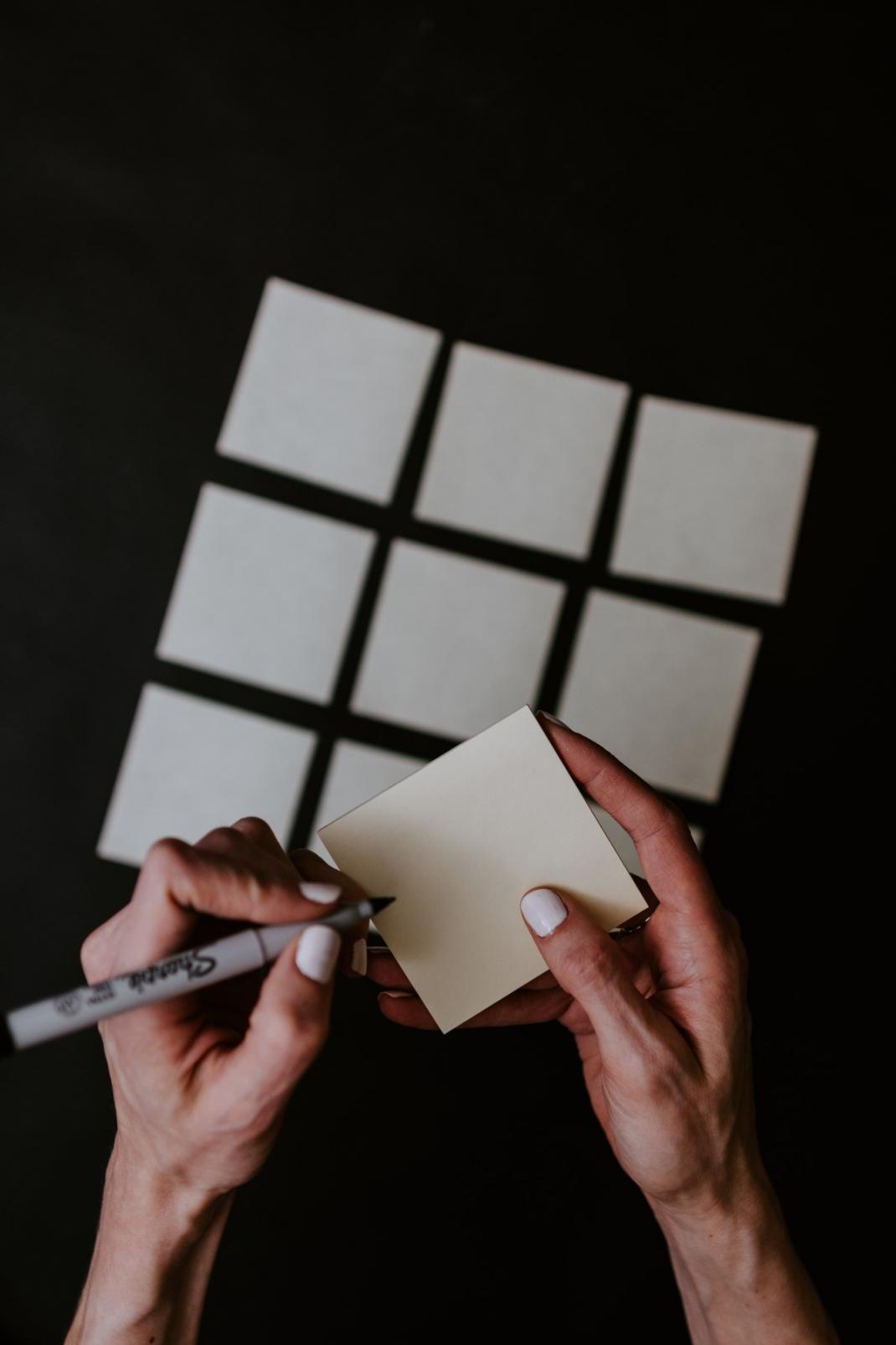 Persoon schrijft met viltstift op post-it briefje
