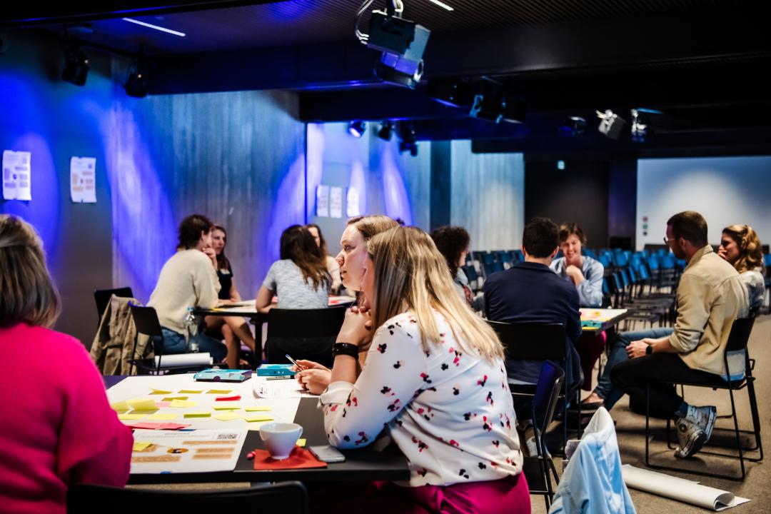 Verschillende mensen zitten aan tafel en zijn in gesprek.